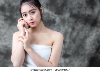 Asia beautiful woman with natural makeup and clean skin wear white towel posting in studio and black background.