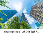 Asia Business concept for real estate, corporate construction and ecology - looking up view of panoramic modern city skyline with blue sky and green tree in Azabudai Hills, tokyo, japan