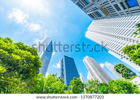 Asia Business concept for real estate, corporate construction and ecology - looking up view of panoramic modern city skyline with blue sky and green tree in shinjuku, tokyo, japan