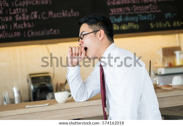 Asia businessman not fesh, Sleepy and yawning,\
coffee shop background