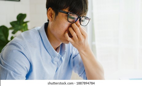 Asia businessman using laptop being upset about work, tearing papers and screaming in living room at home. Working from home, remotely work, social distancing, quarantine for corona virus prevention.