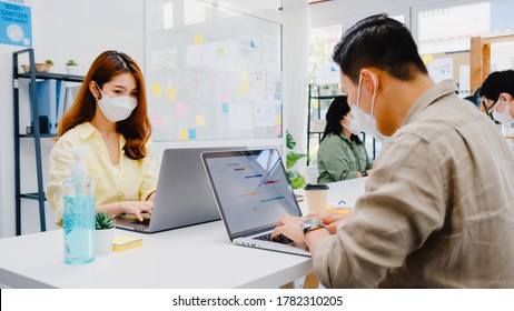 Asia Businesspeople Entrepreneur Wearing Medical Face Mask For Social Distancing In New Normal Situation For Virus Prevention While Using Laptop Back At Work In Office. Lifestyle After Corona Virus.