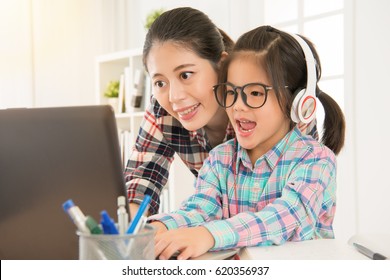 Asia Chinese Beautiful Mom Teaching Little Daughter Learning Online. Pretty Children Wear Glasses And Earphone Studying.