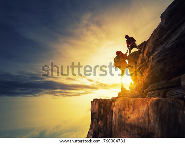 Asia couple hiking help each other silhouette\
in mountains with\
sunlight.