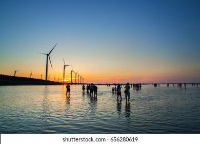Asia culture - Beautiful landscape of sea level reflect fantasy dramatic sunset sky and people's silhouette in Gaomei wetlands , the famous travel attractions in Taichung, Taiwan.