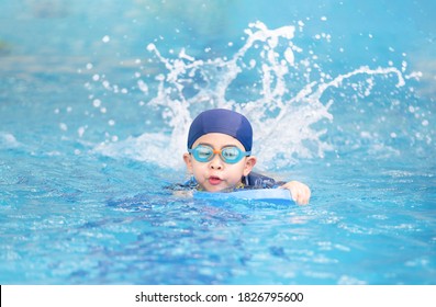 Asia cute boy wearing swimming suit and goggles used foam to practice swimming in swimming pool. Healthy kid enjoying active lifestyle. Refreshing and relax to exercise on summer holiday