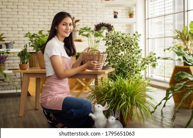 Asia Entrepreneur Beauty Woman Sitting And Holding Plant In Indoor Garden.smiley Face Gardener Wearing Apron In Plants Shop