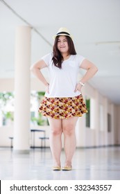 Asia Fat Woman Overweight In White T Shirt And Colorful Skirt With Tree And Building Background