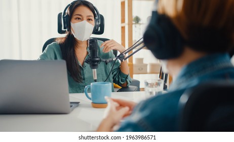 Asia girl radio host record podcast use microphone wear headphone interview guest content wear mask protect virus conversation talk and listen in her room. Podcast from home, coronavirus quarantine. - Powered by Shutterstock