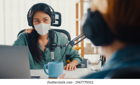 Asia girl radio host record podcast use microphone wear headphone interview guest content wear mask protect virus conversation talk and listen in her room. Podcast from home, coronavirus quarantine. - Powered by Shutterstock