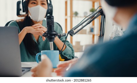 Asia girl radio host record podcast use microphone wear headphone interview guest content wear mask protect virus conversation talk and listen in her room. Podcast from home, coronavirus quarantine. - Powered by Shutterstock