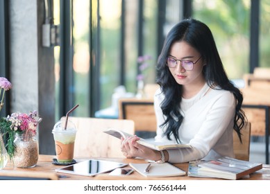 Asia Girl Reading A Book At The Cafe