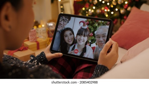 Asia happy woman relax smile laugh waving hand greet in digital tablet screen remote talk to child friend at night online VoIP Xmas party sit on cozy sofa at home enjoy good warm time winter season. - Powered by Shutterstock