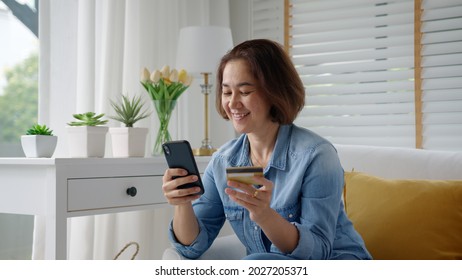 Asia Hispanic Senior People Sit Relax Comfort Smile At Home Sofa Couch Enjoy Gift Card Typing Wifi Smart Phone Remotely Buy On Social Media E-commerce Retail Shop Store Secure Tech Data Omnichannel.