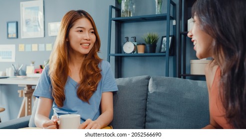 Asia housewife women with casual relax on couch with cup of tea talk together about their life and husband relationship gossip in living room at house. Girls friends roommate stay in dorm together. - Shutterstock ID 2052566690