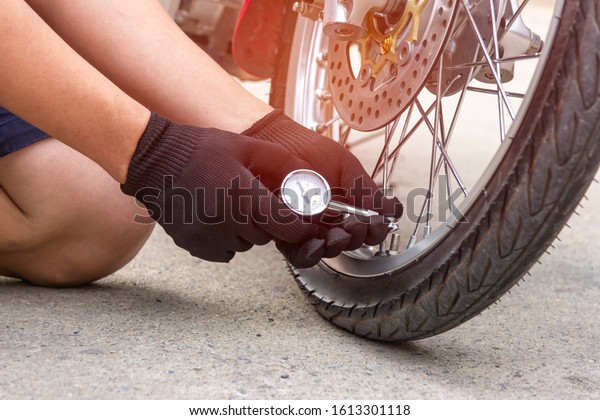 Asia man check\
inflator pressure of the tires motorcycle with Tire monitoring\
equipment analog meter on road\
