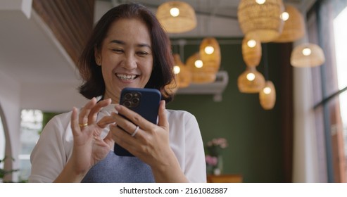 Asia mature adult woman people wear apron small cafe receive e-mail text good news SME lending service solution win seller store in social media app. Shock smile laugh face in sale order reopen shop. - Powered by Shutterstock - Get 15% off with code: PIKWIZARD15