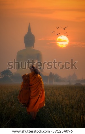 Asia Monk walking behind Big Buddha at Wat Muang Angthong,
temple thailand in sunset.