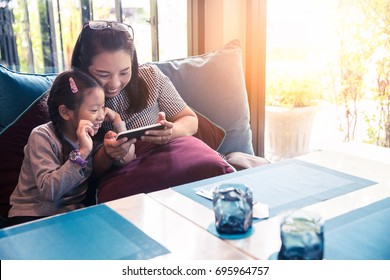 Asia Mother And Daughter Or Kid Enjoy Playing Smartphone, Happy Family Using Mobile Phone