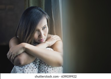 Asia people mournfully looks out her window / Serious sad woman thinking over a problem / Depression and anxiety disorder concept