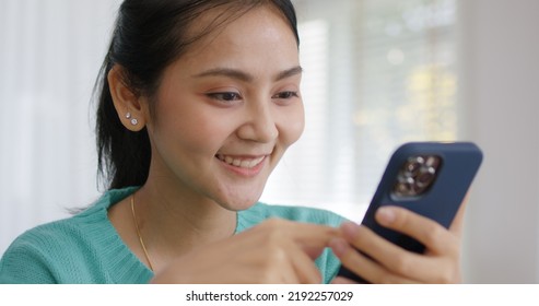 Asia People Single Woman Sit On Desk At Home Read And Look At Man Boy Photo Post On Phone. Relax Smile Choose Lover Enjoy Play Right Swipe On Tinder App To Find Love Couple In Fun Match Flirt Chat.