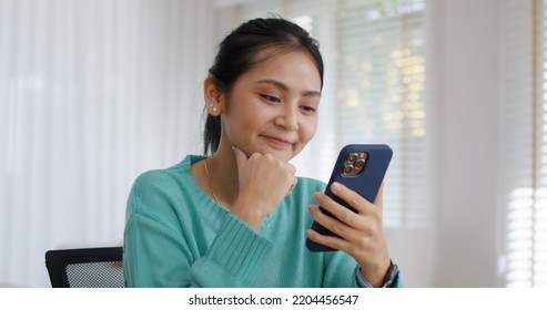 Asia people single woman sit on desk at home read and look at man boy photo post on phone. Relax smile choose lover enjoy play right swipe on tinder app to find love couple in fun match flirt chat. - Powered by Shutterstock