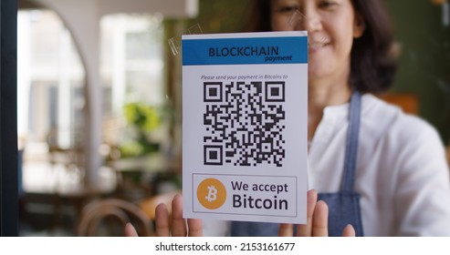 Asia people small SME owner stick QR code placard text label signage poster on glass virtual cash digital money service. Cryptocurrency Bitcoin ethereum blockchain logo on modern coffee cafe shop.  