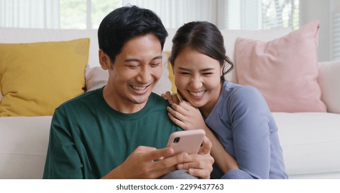 Asia people young family man woman smile happy fun laugh look at phone sit at home pay for hotel booking, search choose, buy ticket on social media app for budget travel abroad trip getaway plan tour. - Powered by Shutterstock