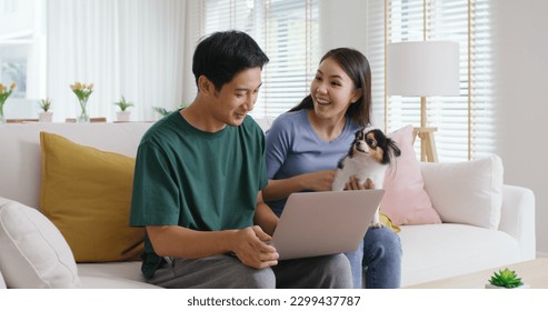 Asia people young family man woman smile happy sit at home sofa couch pay for hotel booking, search choose, buy ticket on laptop social media app travel trip getaway plan tour with cute small pet dog. - Powered by Shutterstock