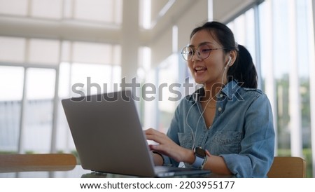 Asia people young girl relax smile video call talk on laptop sit learn study online class reskill career upskill job hybrid workation at modern coworking workspace share office in future workforce.