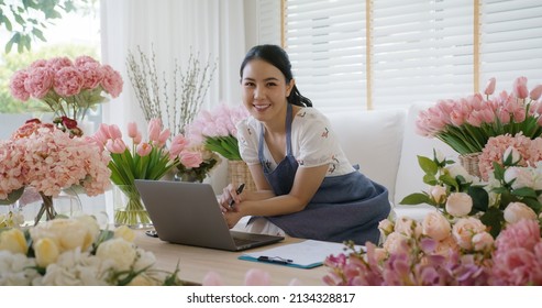 Asia people young woman SME owner happy smile look at camera enjoy open flower shop sale order web page work at home office workspace. Loan money banking for social media commerce online store seller. - Powered by Shutterstock