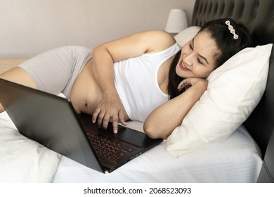 Asia Pregnant Mother Use A Computer For Online Shopping  On The Bedroom. She Smile And  Very Happy To See The Baby.The Idea Of Buying Baby Supplies