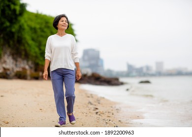 Asia Senior Happy Woman Is Walk And Exercise On The Calm Beach In The Morning Alone.