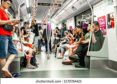 Asia / Singapore - Nov 23, 2019 : Public Transportation Subway MRT Train Crowded With Asian People, Most Of Them Looking And Using Their Mobile Phone Devices