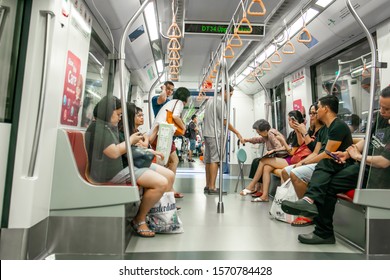 Asia / Singapore - Nov 23, 2019 : Public Transportation Subway MRT Train Crowded With Asian People, Most Of Them Looking And Using Their Mobile Phone Devices