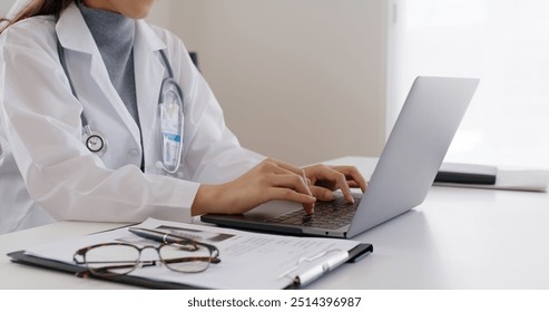 Asia smart people female GP hands chat on telehealth telemedicine teleconsult app to online patient on laptop sit work at clinic office desk, enter Rx exam record data, share lab blog or write e-mail. - Powered by Shutterstock