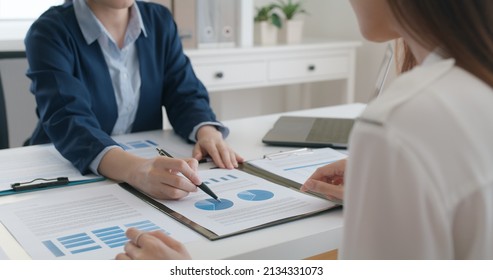 Asia stock trader agent or Sale tax loan broker advice brief and point hand to graph report talk to client at office desk show budget chart data or legal result on claim form. Trust will in work plan. - Shutterstock ID 2134331073