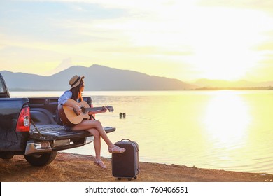 Asia traveler sitting hatchback car and playing guitar when sunset near the lake on holiday.beautiful tourist watch view of nature on vacation. - Powered by Shutterstock