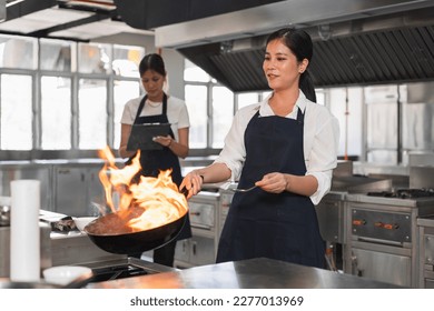 Asia woman chef in the professional kitchen with a frying pan and a fire	 - Powered by Shutterstock