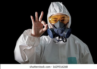 Asia woman o.k hand sign in a chemical protective clothing and 
Woman in chemical protective clothing and half mask replaceable particulate filter respirator  with glasses at black background - Powered by Shutterstock