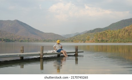 Asia Woman People Enjoy Staycation Pet Owner Getaway Good Time Day With Small Puppy Dog Lover Sit Relax Happy Care Hug And Kiss Cute Friend At Rural Calm Lake Pier With Blue Sky In Nature Trip Life.