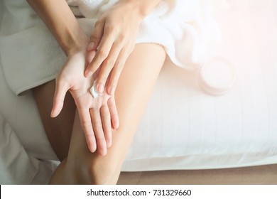 Asia woman sitting on bed and applying cream on Hand.