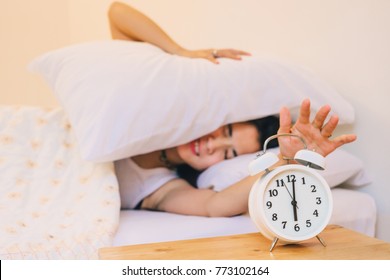 Asia woman sleepy don't want to get up at 6.00 A.M. by alarm clock.beautiful lady angry ring of alarm clock in the morning. - Shutterstock ID 773102164