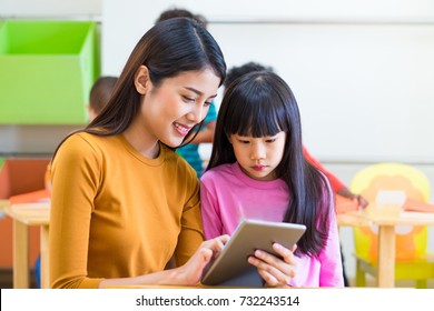 Asia woman teacher teach girl student with tablet computer in classroom at kindergarten preschool,Online education concept,e-learning