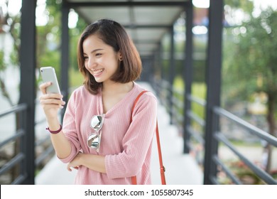 Asia woman using with smart phone in the street in a sunny summer day