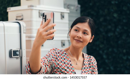 Asia woman using smartphone in front of large luggage - Shutterstock ID 1453017557