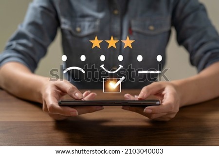 Asia woman using smartphone for select smiley face icon for client evaluation and customer satisfaction after use product and service concept.

