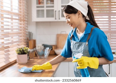 Asia woman in workwear maid cleaning home and wiping the table with microfiber cloth in kitchen room at home - Shutterstock ID 2332560869
