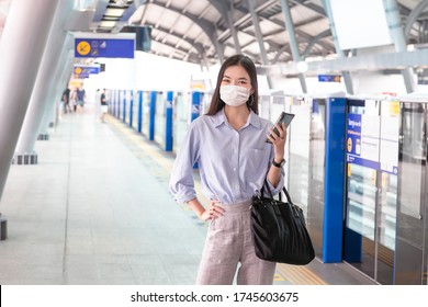 Asia Working Woman Going To Work And Wearing Hygienic Mask Prevent Corona Virus And Playing Tablet Computer In Monorail Subway Station.new Normal 