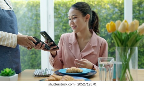 Asia young smile happy woman people in small sme coffee shop store use tapping cashless wifi qr code nfc scan app smart pos device reader sale in food drink order in cafe urban city life contactless. - Powered by Shutterstock